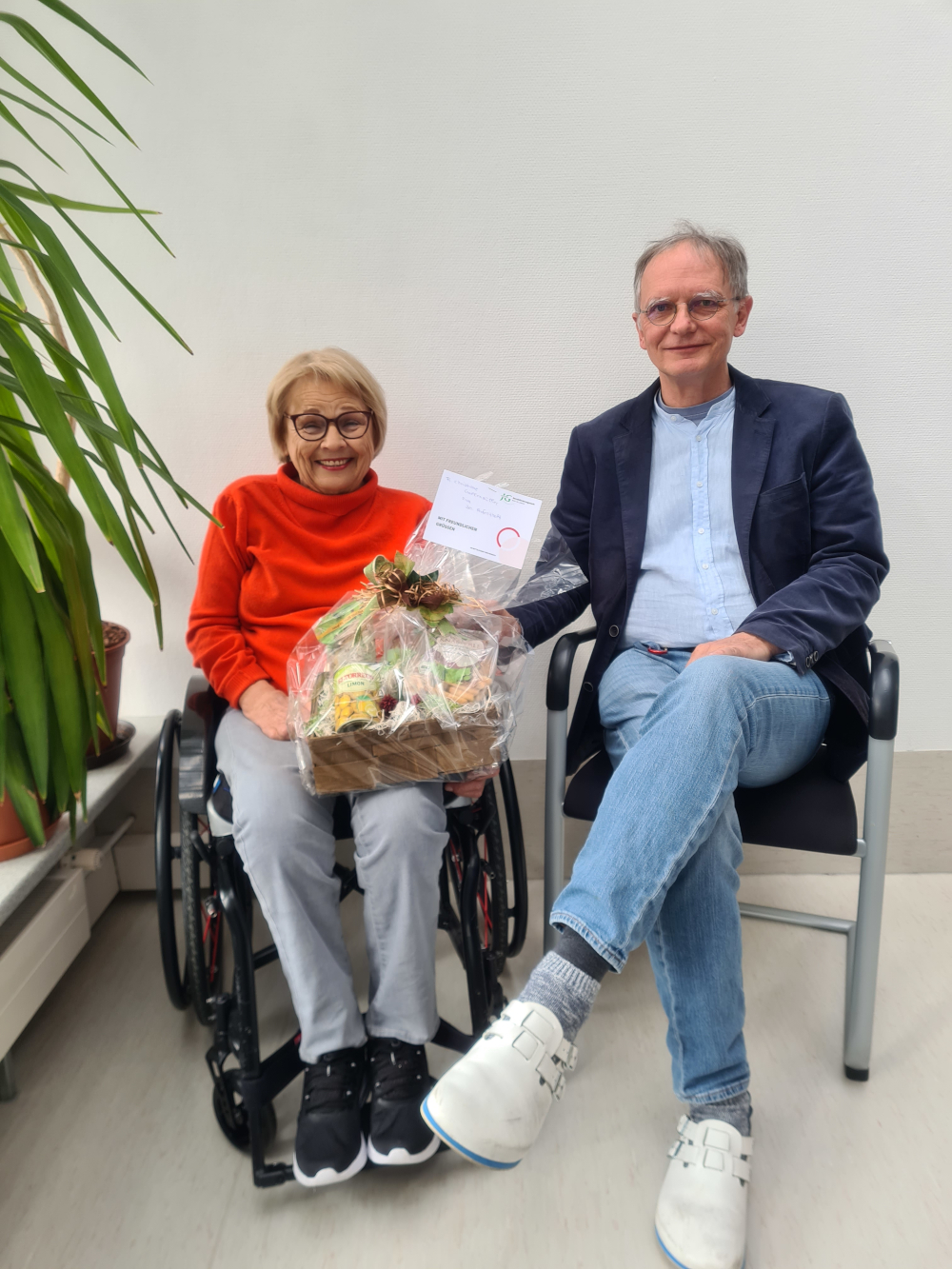 Chefarzt Dr. Moosburger überreicht Patientin einen Präsentkorb